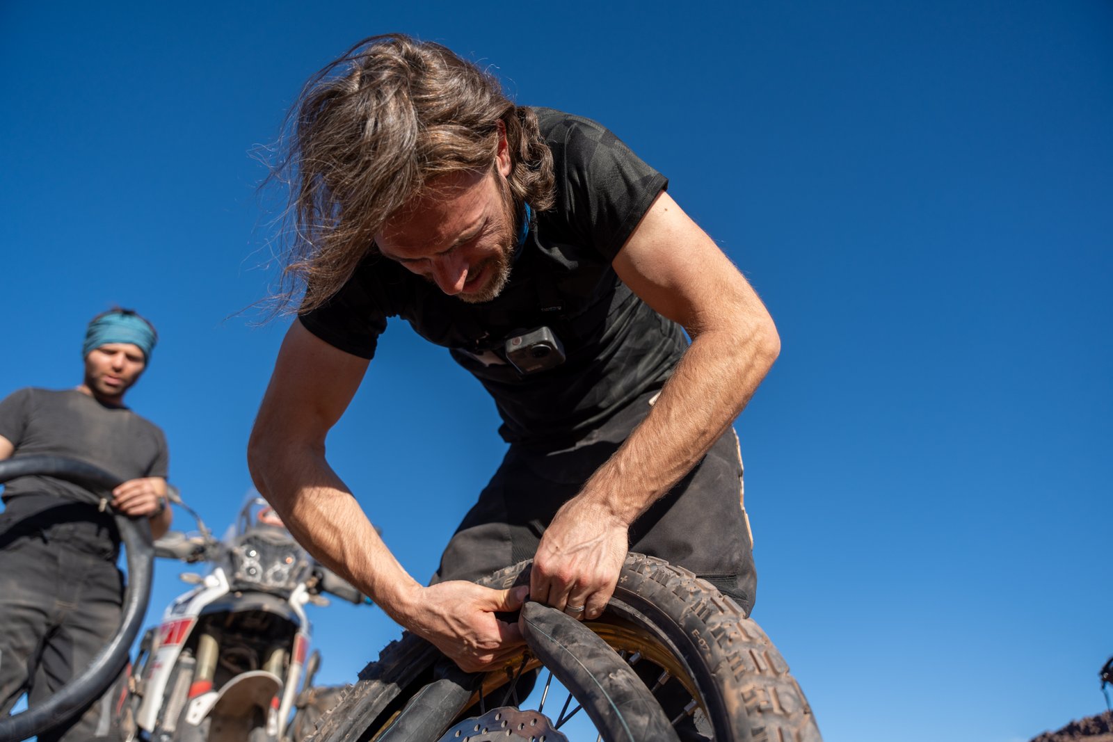 Riders repairing a motorcycle tire in the desert